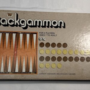 May include: A rectangular cardboard box for a Backgammon board game. The tan box features the word Backgammon in black text, an illustration of the game board, two white dice, and thirty plastic checkers in brown and yellow colors.