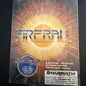 May include: A rectangular video game box for Fireball, a Supercharger game for the Atari Video Computer System. The cover features a bright yellow sunburst graphic, the Starpath Corporation logo, and text stating a cassette player is required.