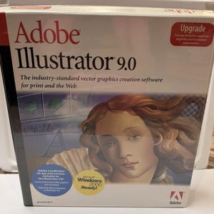 May include: A retail box for Adobe Illustrator 9.0 software. The box features the product name, the text The industry-standard vector graphics creation software for print and the Web, a Windows 2000 Ready seal, and an illustration of a person.