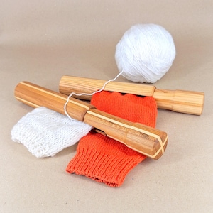 Könnte beinhalten: Sockenblocker aus hellem Holz mit Kontraststreifen, kombiniert mit orangefarbenen und weißen Stricksocken und einem Knäuel weißer Wolle. Die Sockenblocker dienen zum Formen und Trocknen handgestrickter Socken.