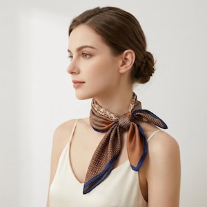 May include: A square silk scarf tied around the neck, featuring a brown base with a repeating geometric pattern of small white dots and a dark blue border. The scarf also displays a section with a tan and brown floral motif near the knot.