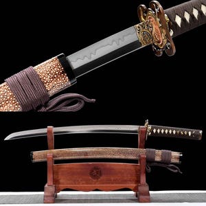Könnte beinhalten: Ein japanisches Katana-Schwert mit einer gebogenen Stahlklinge mit wellenförmiger Hamon-Linie, einem dunkelbraun umwickelten Griff und einem verzierten goldfarbenen Stichblatt. Die Scheide ist mit einer gesprenkelten cremefarbenen Oberfläche.