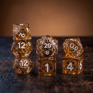 Op de afbeelding: Een set veelzijdige dobbelstenen gemaakt van heldere amberkleurige hars met ingebedde metalen uurwerk tandwielen. De dobbelstenen hebben witte cijfers en bevatten een d20, d12, d10, d8, d6 en d4, gerangschikt in een stapel en twee aparte groepen.
