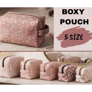 May include: A collection of five boxy pouches in varying sizes, each featuring a dusty rose floral pattern, a top zipper closure, and a side handle. The text "BOXY POUCH" and "5 SIZE" is displayed in black and dark pink on the right side of the image.