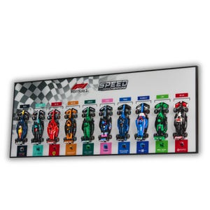 May include: A rectangular wall display featuring ten miniature Formula 1 race cars arranged in a row. The white background includes a checkered flag pattern, the Formula 1 logo, and the text Speed Champions. Each car is labeled with its model name.