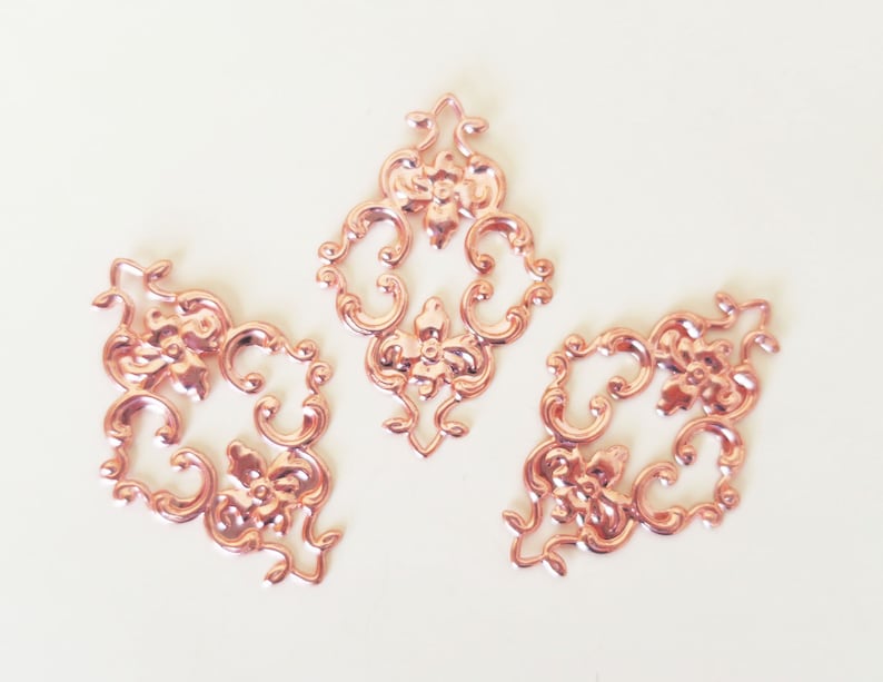 May include: Three rose gold metal decorative embellishments with a floral design.