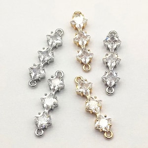 May include: Four silver and gold connector charms with five clear square-shaped rhinestones each. The charms have a loop on each end.