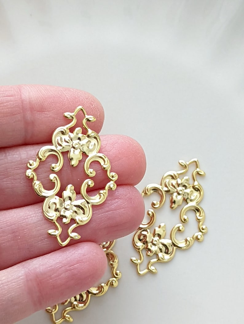 May include: Gold metal decorative embellishments with a floral design. The embellishments are intricate and detailed, with a delicate scrollwork pattern.