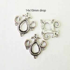 以下が含まれることがあります： 装飾的なデザインが施された銀色の金属製チャームが3つ。各チャームは、複雑なスクロールワークが施された涙滴の形をしています。チャームのサイズは14mm x 10mmです。