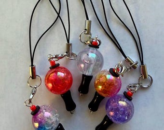 May include: Five phone charms featuring spherical beads with iridescent, glittery finishes in red, clear, orange, purple, and blue-purple. Each charm has a black handle, a small red bead accent, a silver-tone metal jump ring, and a black cord loop.