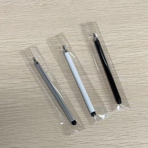 以下が含まれることがあります： 透明なプラスチック製のスリーブに個別に包装された、3本の細いスタイラスペン。シルバー、ホワイト、ブラックの各スタイラスペンがセットになっており、すべて上部に金属製のアクセントと、タッチスクリーン操作用の丸みを帯びた黒いペン先が付いています。