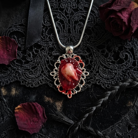 A hand-crafted bloody wisdom tooth pendant that walks the line between body horror and wearable art — genuinely unsettling in the best way.