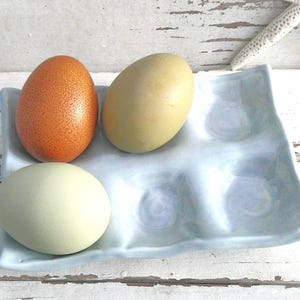 May include: A white ceramic mug with a black handle and the text "But First, Coffee" in a black, bold font. The mug is sitting on a wooden surface. The mug is 4 inches tall.