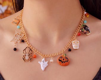 May include: A gold-tone chain necklace featuring various Halloween-themed charms including a white ghost, an orange jack-o'-lantern, a black spider, a white skull, a spiderweb, and a rectangular charm with the text "Trick or Treat" in gold.