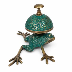 May include: A brass desk bell featuring a frog-shaped base with a verdigris green patina finish. The bell dome has a textured, scale-like pattern in green and brass, topped with a small, smooth, circular brass button for activation.