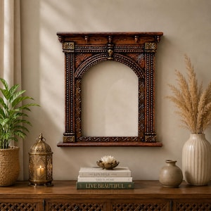 May include: A rectangular wall mirror featuring a dark brown wooden frame with an arched top, intricate carved detailing, and gold-toned accents. The frame includes a small shelf at the base and decorative columns on both sides of the central glass.