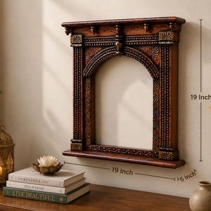May include: A dark brown wooden wall frame with an arched opening and intricate carved details. The frame features a top shelf and a bottom shelf, measuring 48.26 cm in height, 48.26 cm in width, and 12.7 cm in depth as indicated by text.