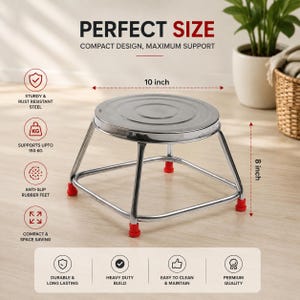 Op de afbeelding: Een zilverkleurige metalen kruk met een rond blad en vier poten met rode antislip rubberen voetjes. De kruk heeft een diameter van 25,4 cm en een hoogte van 20,32 cm, met tekst die wijst op een constructie van roestbestendig staal.
