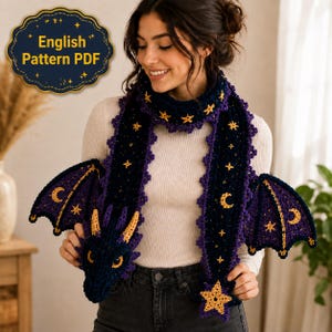 May include: A dark blue crochet dragon scarf featuring yellow embroidered stars and crescent moons, with attached dragon wings and a dragon head at one end. The scarf includes a scalloped edge and a star at the tip. Text reads English Pattern PDF.