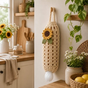 May include: A cream-colored crochet plastic bag dispenser featuring an open-weave grid pattern and a hanging loop. The dispenser is decorated with a crocheted sunflower applique with yellow petals, a brown center, and two green leaves.