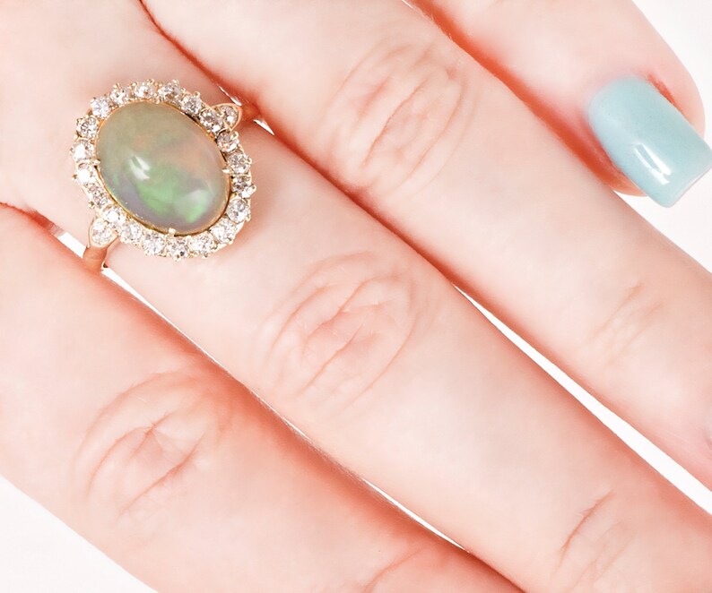 May include: A gold ring with a large oval opal gemstone surrounded by a halo of smaller diamonds.