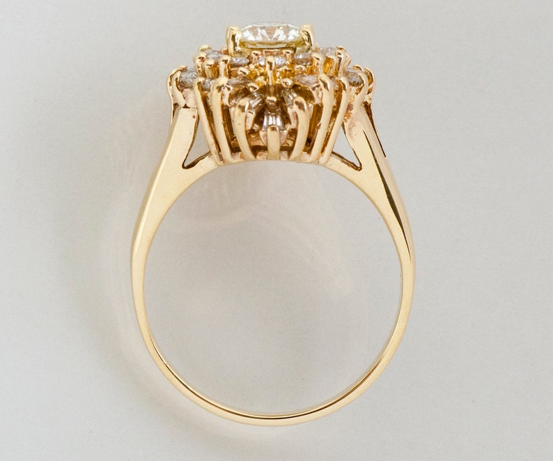 May include: A gold ring featuring a cluster of diamonds. The central diamond is surrounded by smaller stones, creating a floral or starburst design. The band is a simple, polished gold.