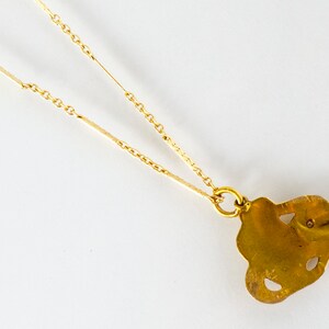 May include: A gold chain necklace with a gold pendant shaped like a stylized heart. The pendant has a small diamond in the center.