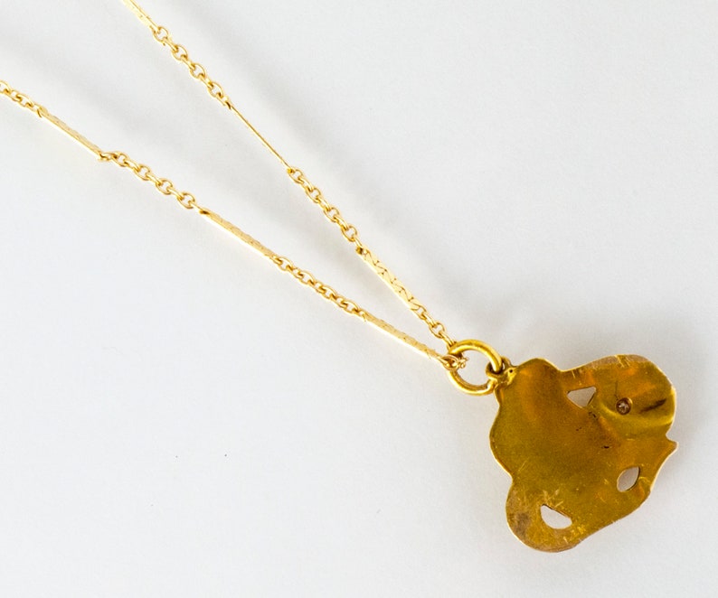 May include: A gold chain necklace with a gold pendant shaped like a stylized heart. The pendant has a small diamond in the center.