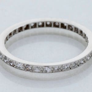 May include: A thin silver band with a row of small diamonds set in a continuous line around the edge.