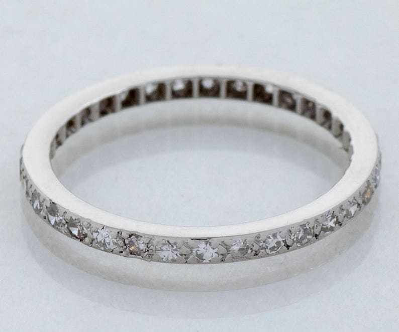 May include: A thin silver band with a row of small diamonds set in a continuous line around the edge.