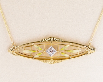 May include: A gold necklace with a delicate, oval-shaped pendant featuring a diamond set in a geometric design. The pendant is surrounded by a delicate, openwork design with a yellow enamel finish.
