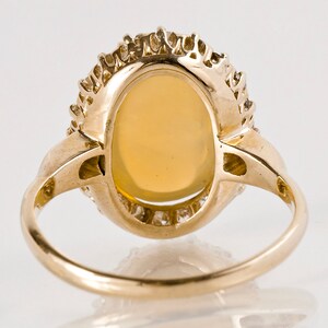 May include: A gold ring with an oval-shaped opal gemstone surrounded by a halo of smaller diamonds.