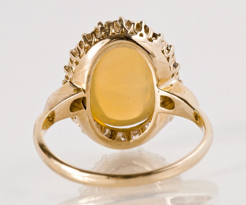 May include: A gold ring with an oval-shaped opal gemstone surrounded by a halo of smaller diamonds.