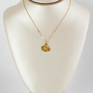 May include: A gold chain necklace with a pendant featuring a detailed design of a woman's face.