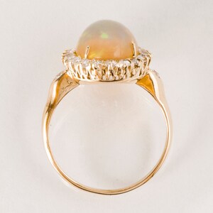 May include: A gold ring with a large opal gemstone surrounded by a halo of smaller diamonds.