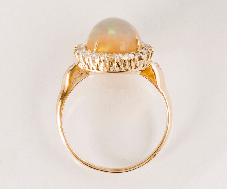 May include: A gold ring with a large opal gemstone surrounded by a halo of smaller diamonds.