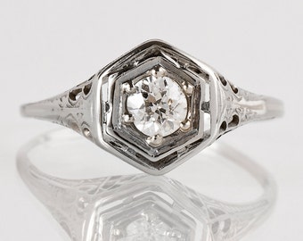 May include: A silver ring with a hexagonal setting featuring a single round diamond.