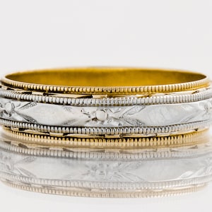 Könnte beinhalten: Ein goldener und weißer Ehering mit einem detaillierten gravierten Design.