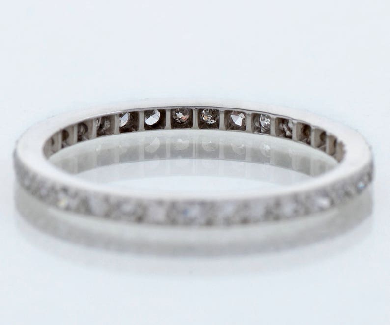 May include: A silver band ring with a row of small diamonds set in a channel setting.