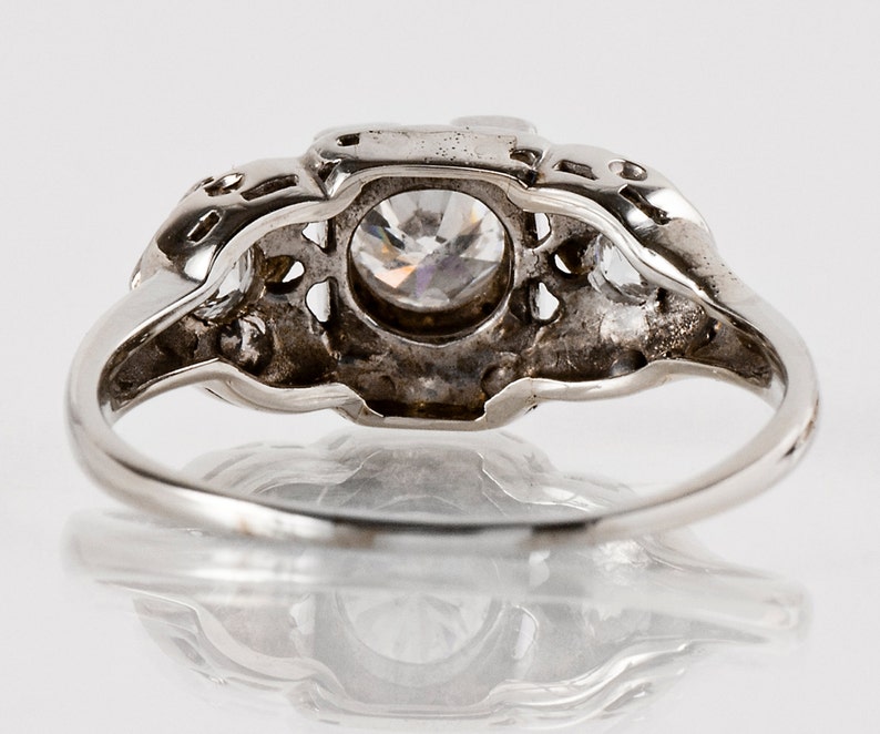 Puede incluir: Un anillo de plata con una gran piedra preciosa transparente rodeada de piedras preciosas m&aacute;s peque&ntilde;as. El anillo tiene un dise&ntilde;o delicado e intrincado.