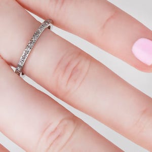 May include: A thin silver band with small diamonds set in a pave setting.