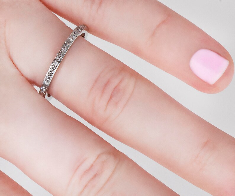 May include: A thin silver band with small diamonds set in a pave setting.