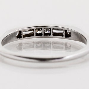 May include: A silver band ring with five small diamonds set in a row. The diamonds are clear and sparkly.