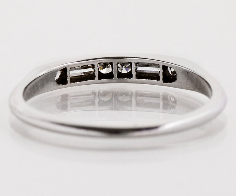 May include: A silver band ring with five small diamonds set in a row. The diamonds are clear and sparkly.