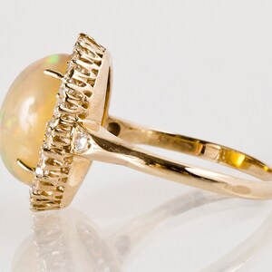 May include: A gold ring with a large oval opal gemstone surrounded by a halo of smaller diamonds.