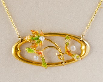 May include: A gold necklace with a pendant featuring a stylized design of leaves and branches with enamel details in green, orange, and yellow. The pendant is oval-shaped and has three small white pearls.