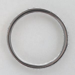 May include: A silver band ring with a row of small diamonds encircling the band.