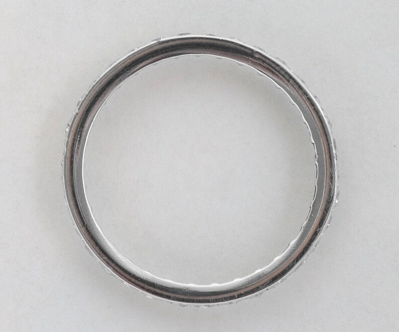 May include: A silver band ring with a row of small diamonds encircling the band.