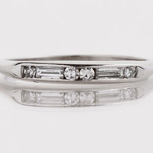 May include: A delicate silver band ring with a row of small round and baguette-shaped diamonds.