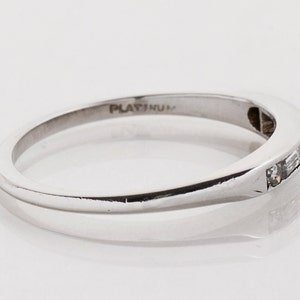 May include: A platinum band ring with a row of small, rectangular diamonds set in the band. The ring is marked "PLATINUM" on the inside.
